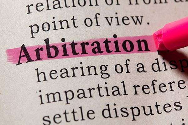 The word Arbitration highlighted in pink in a dictionary beside a pink marker.