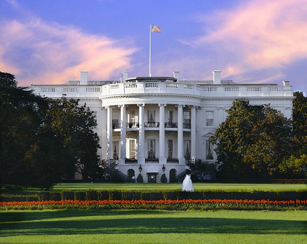 The White House and its lawn beneath a pink and purple evening sky.