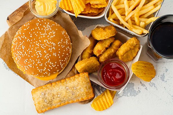 Overhead view of a burger, fries, nuggets, pastry and sauces on a table.
