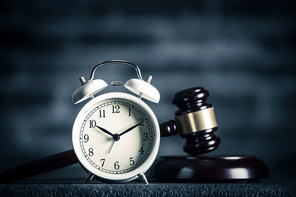 A silver alarm clock stands beside a judge's gavel and sound block.