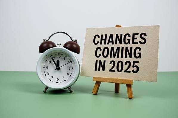 An alarm clock beside a small easel sign reading Changes Coming in 2025.