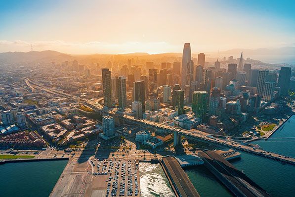 Aerial view of San Francisco's downtown skyline and bay at sunset.