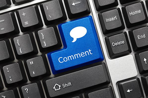 A blue Comment key with a speech-bubble icon on a black keyboard.