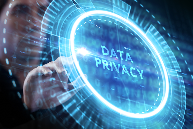Data Privacy lettering glows inside a circular blue digital interface reached toward by a hand.