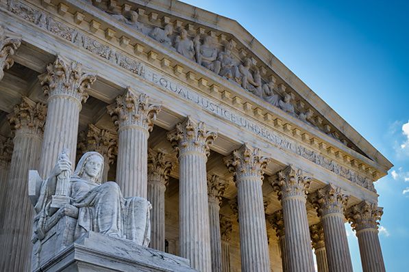 Low-angle view of the U.S. Supreme Court's sculpted pediment, columns and seated statue.