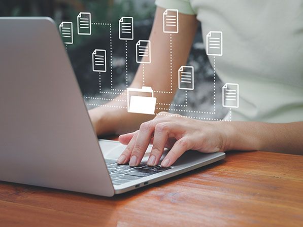 A person types on a laptop beneath overlaid document and folder icons.