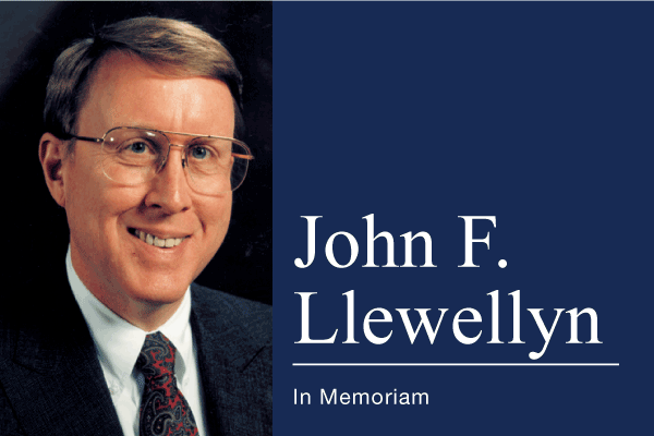 Portrait of John F. Llewellyn beside his name and the words In Memoriam on navy blue.