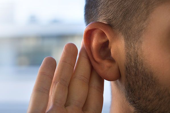 Close-up of a man cupping a hand behind his ear.