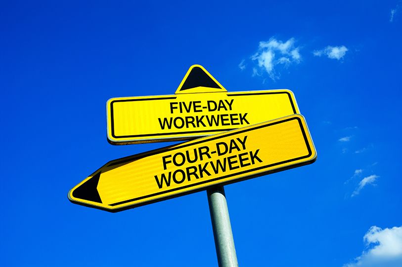 Yellow signs point in different directions for FIVE-DAY WORKWEEK and FOUR-DAY WORKWEEK against a blue sky.
