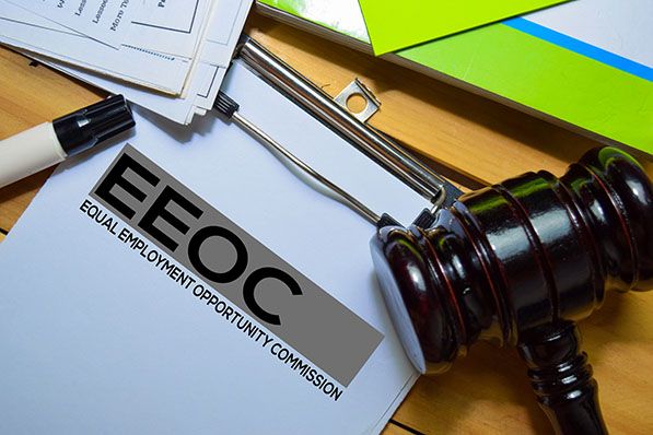 A gavel rests beside a clipboard labeled EEOC, Equal Employment Opportunity Commission.