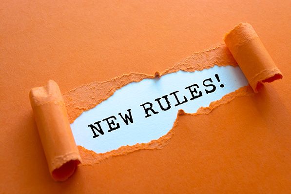 Torn orange paper reveals the words NEW RULES! on a white strip.