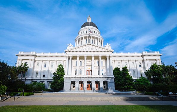Front view of the California State Capitol beneath a bright blue sky.