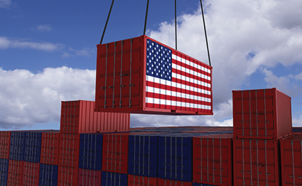 A crane lifts a red shipping container painted with a United States flag above stacked containers.