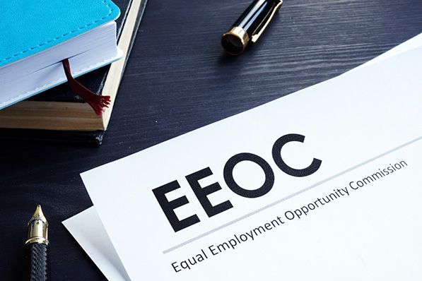 Document headed EEOC, Equal Employment Opportunity Commission, beside books and pens.