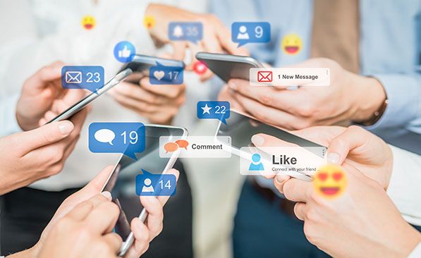 Hands hold smartphones beneath overlaid social media notifications and reaction icons.