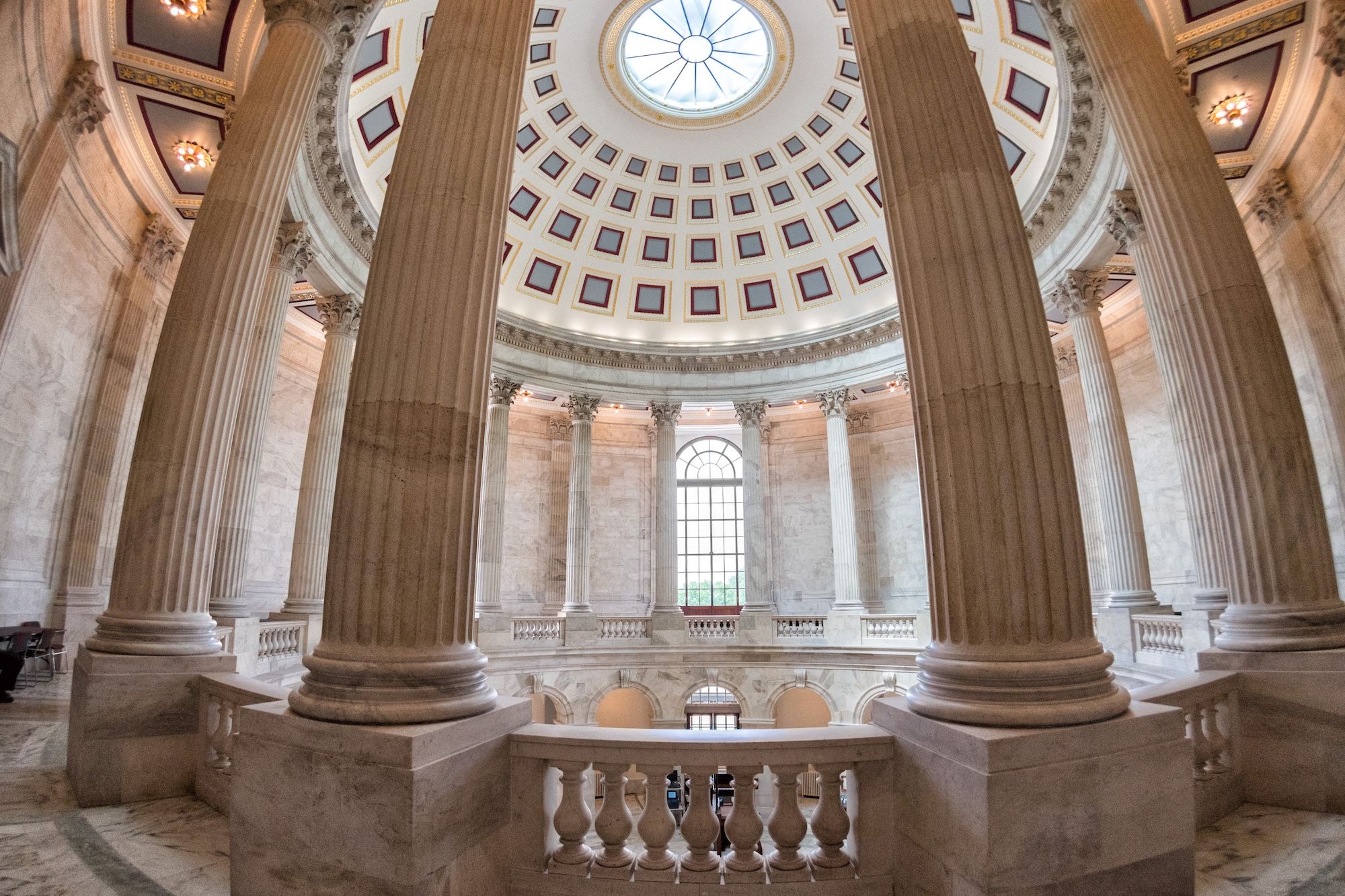 An ornate domed rotunda with tall stone columns, a patterned ceiling and balustrade.