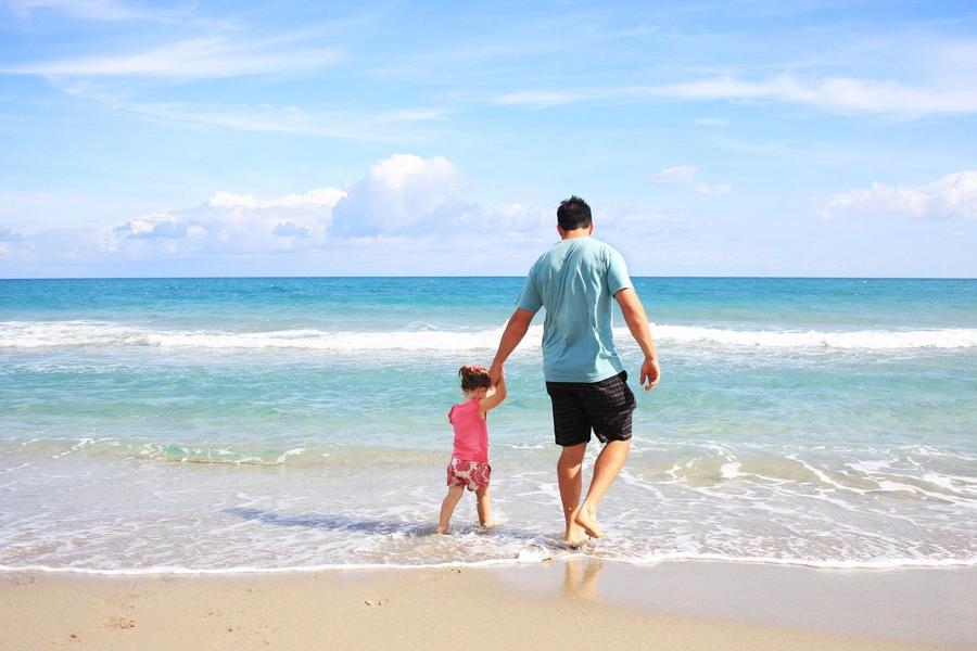 A father and his young daughter walking hand in hand into the surf