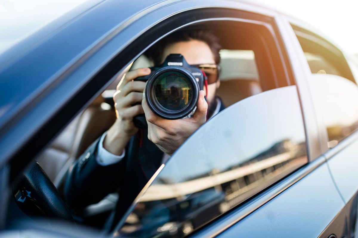 Private investigator in car, taking a photo performing surveillance. 