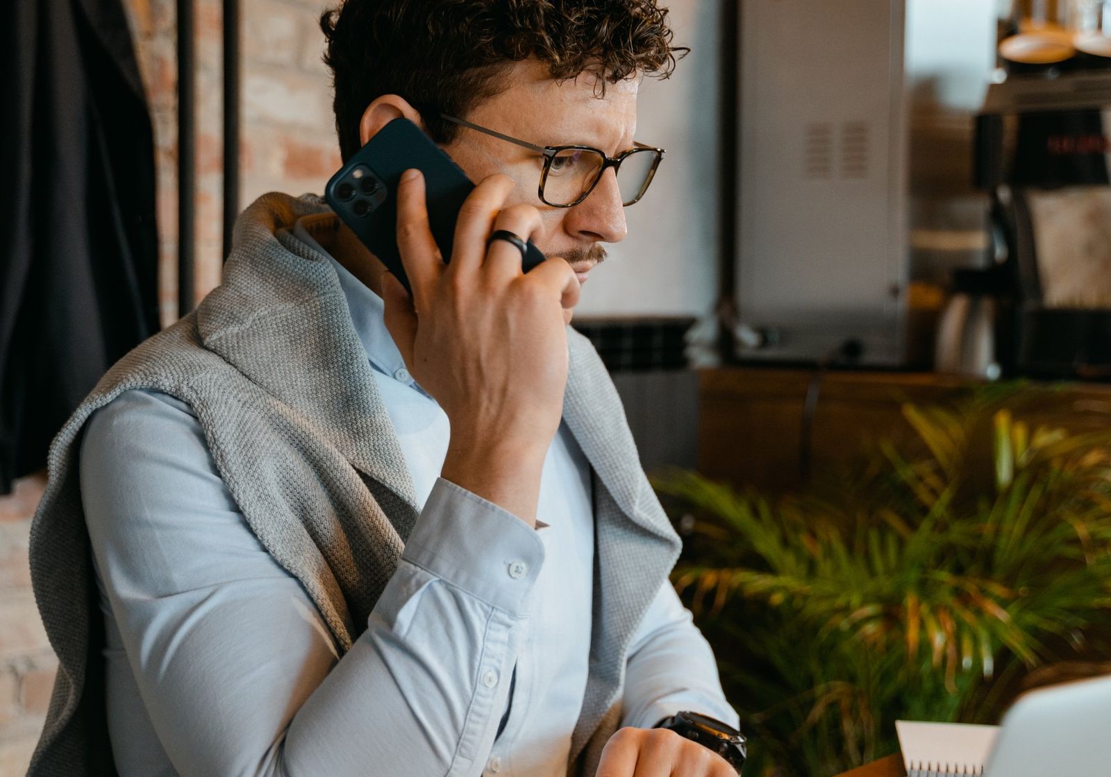 A man taking a call over his laptop at a cafe table