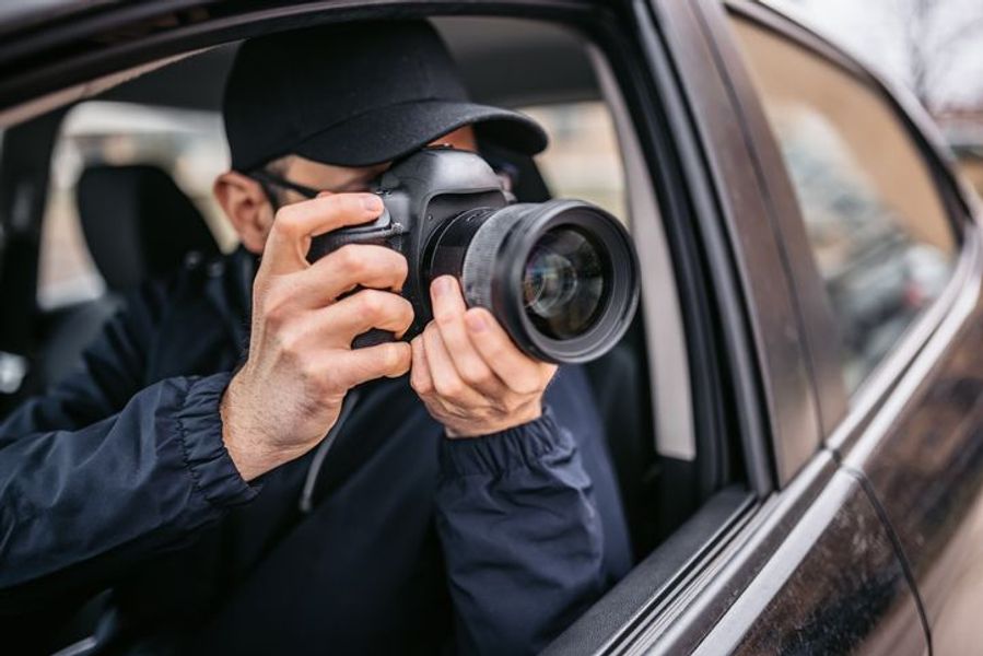 A man in a cap aiming a DSLR out of a car window