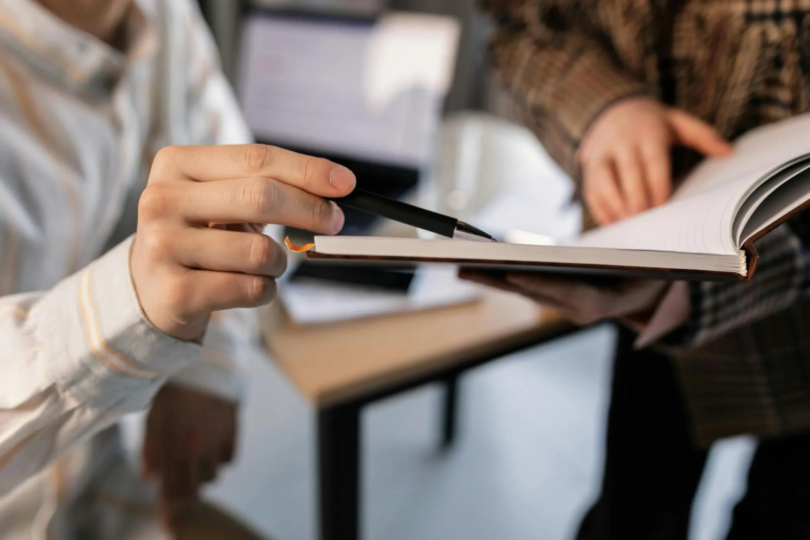 Two people going over handwritten notes together at a desk