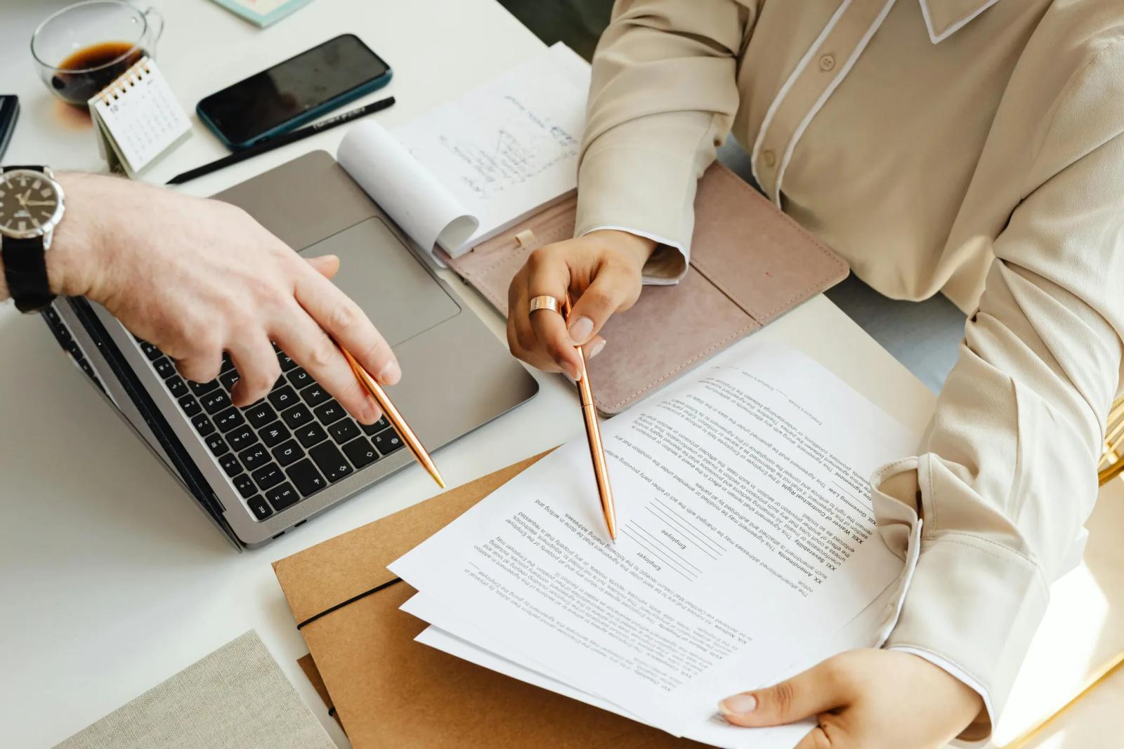 Two people at a desk working through a printed agreement