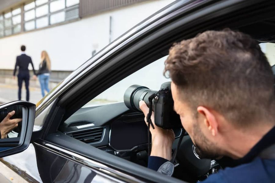 A man photographing a couple from inside a parked car