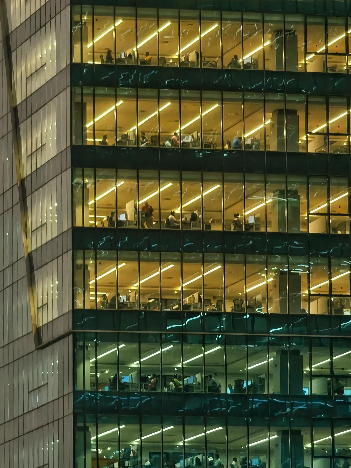 The lit floors of an office tower at night, seen from outside