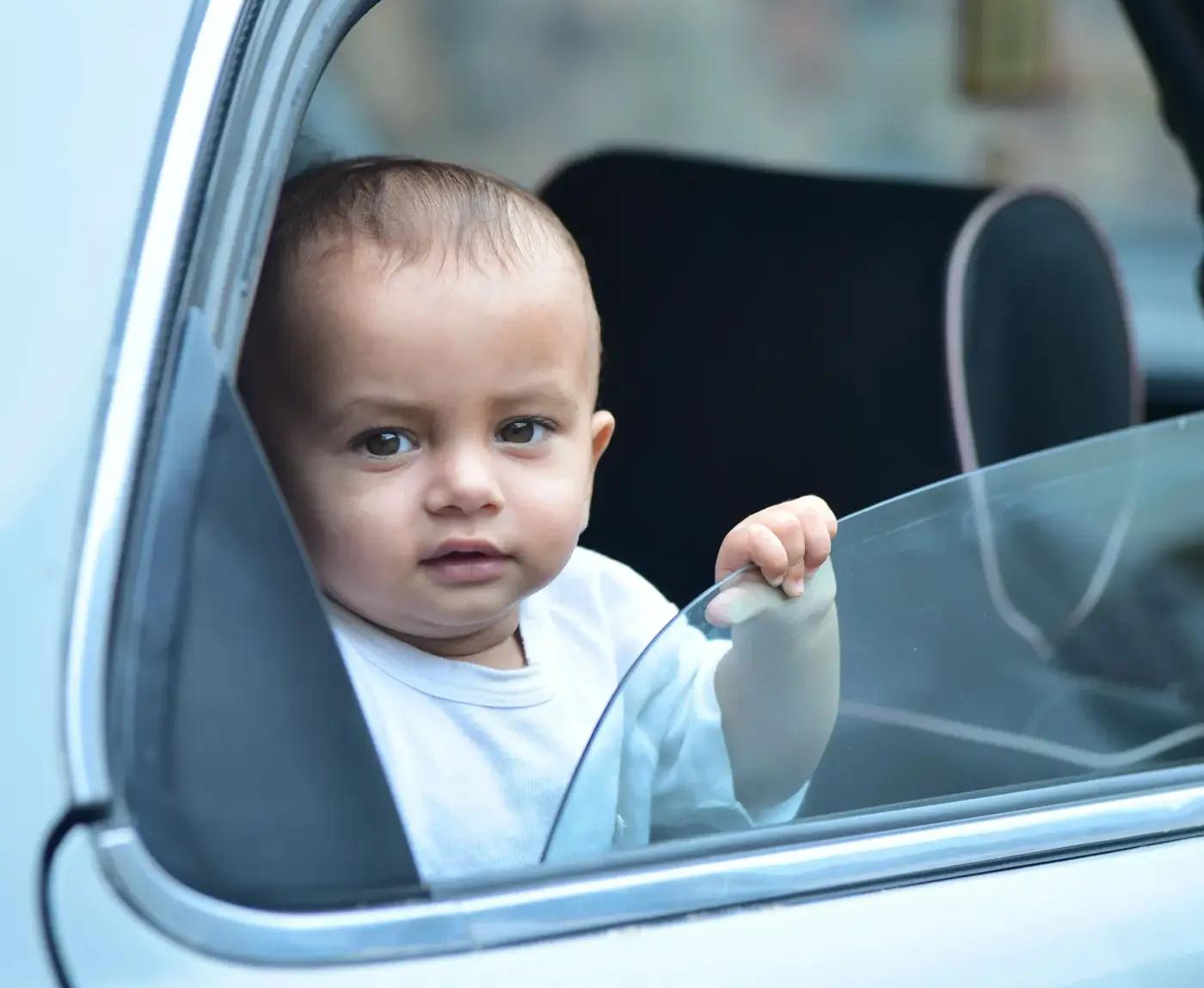 A toddler looking out through an open car window