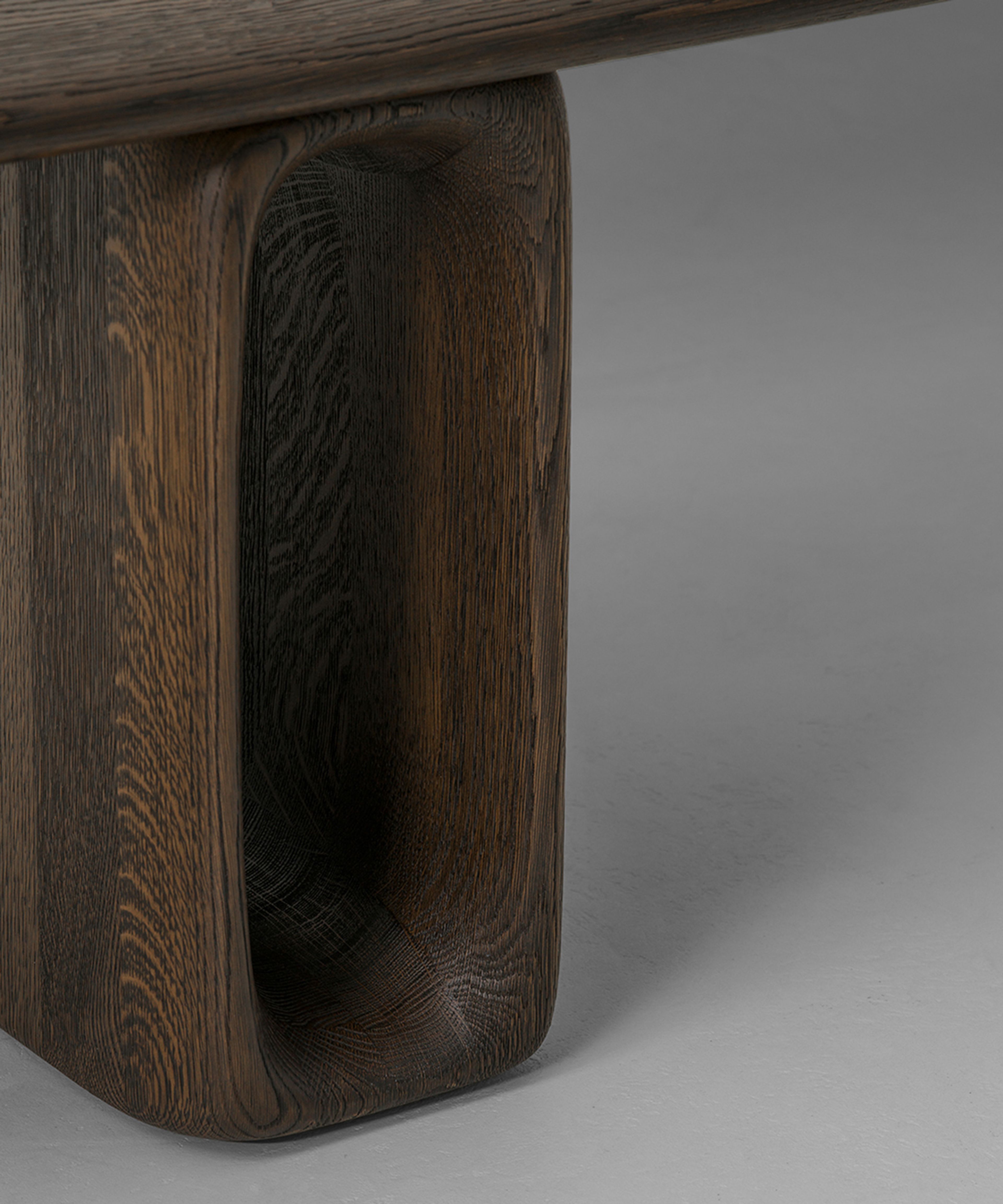 A bench by Van Rossum — oblong oak legs with oval cutouts and a cantilevered seat.