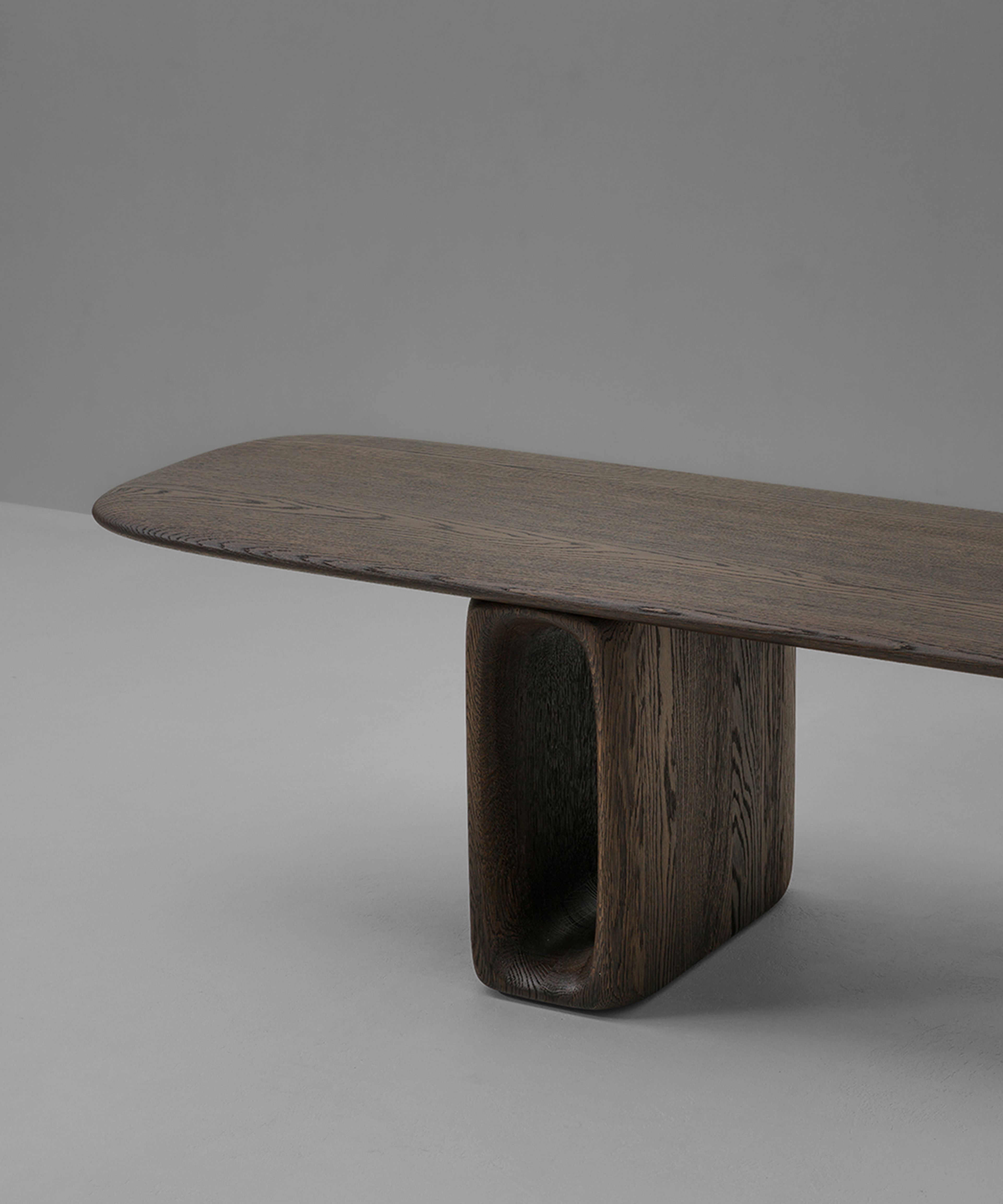 Un banc signé Van Rossum — pieds oblongs en chêne avec découpes ovales et assise en porte-à-faux.