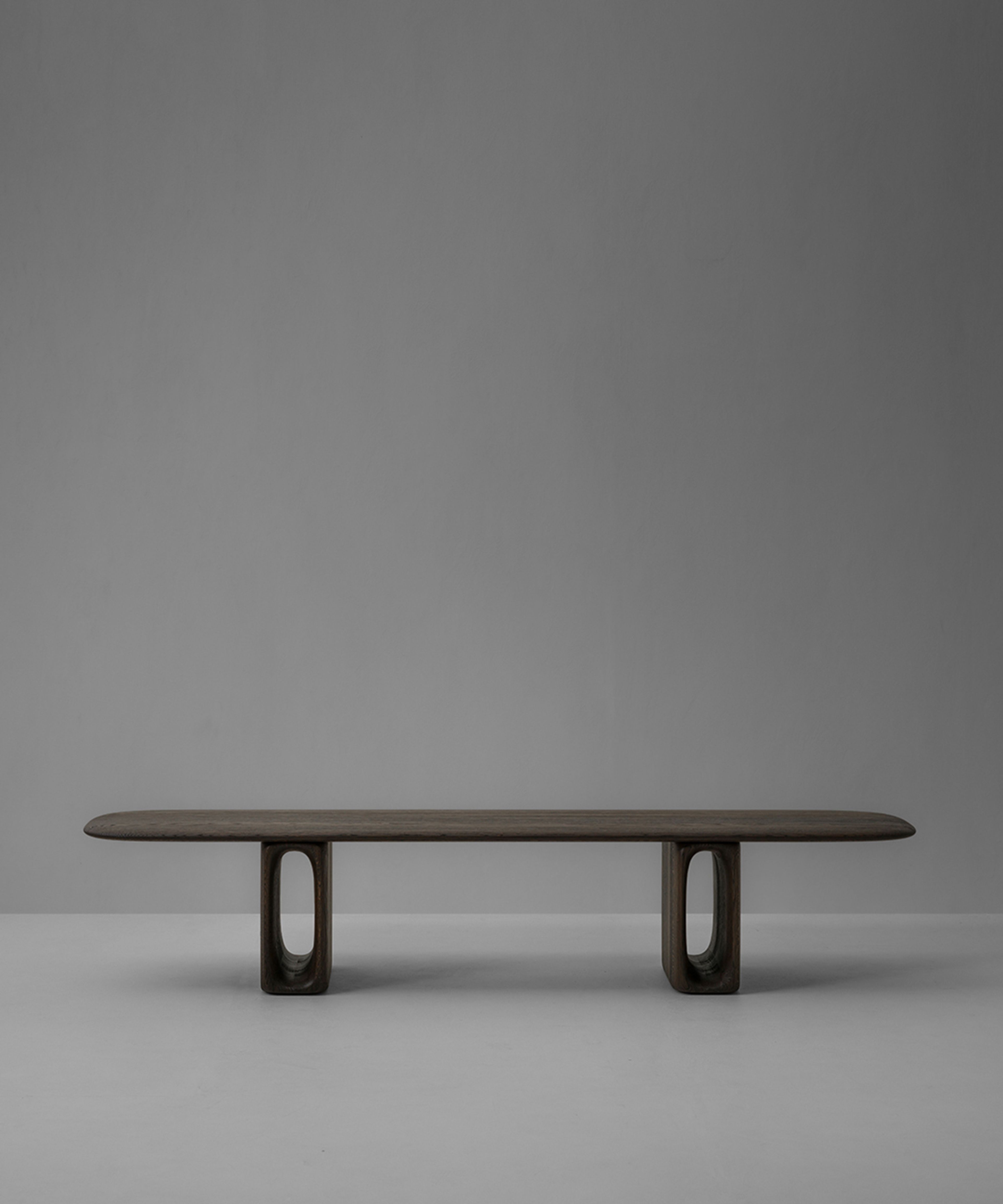 A bench by Van Rossum — oblong oak legs with oval cutouts and a cantilevered seat.