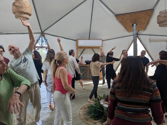People standing with raised hands inside a geodesic dome