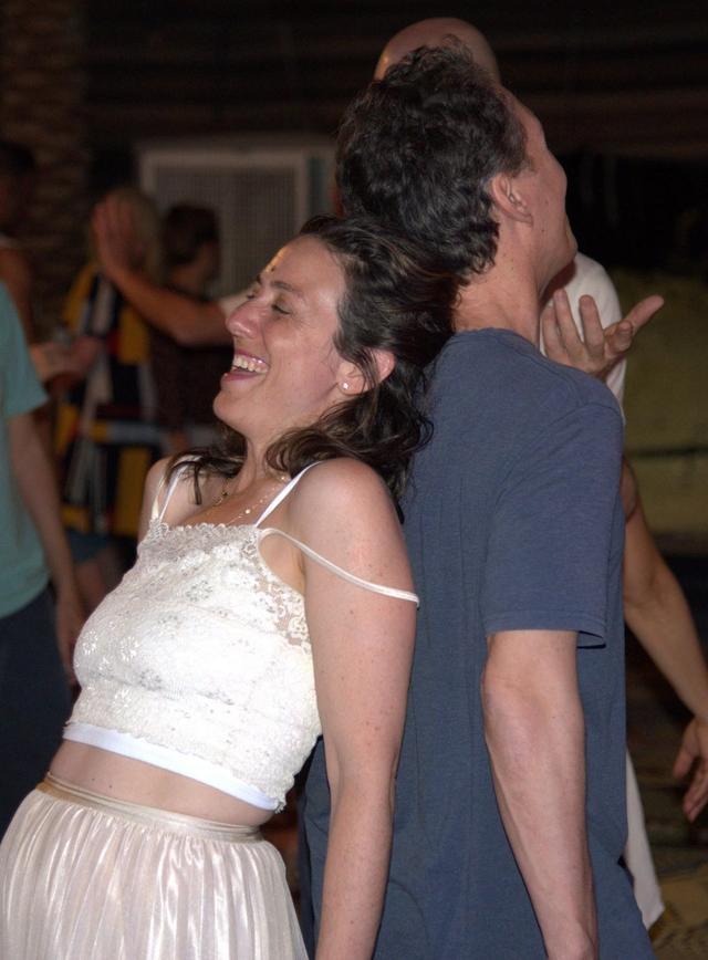 Two people laughing together, standing back to back