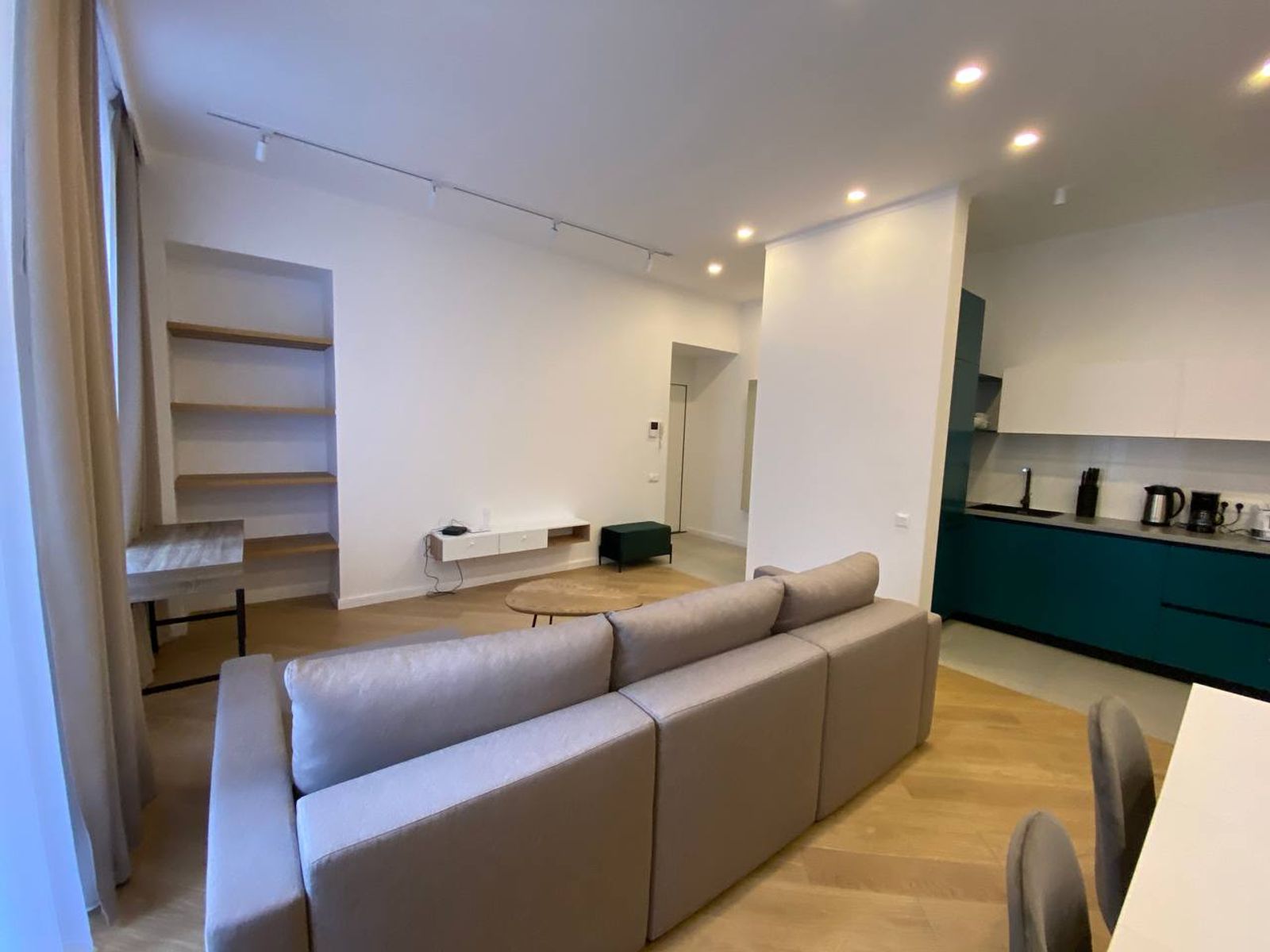 Living room with sectional sofa and teal kitchen cabinets, Olesia Honchara 24B, Kyiv — Vestor.Estate