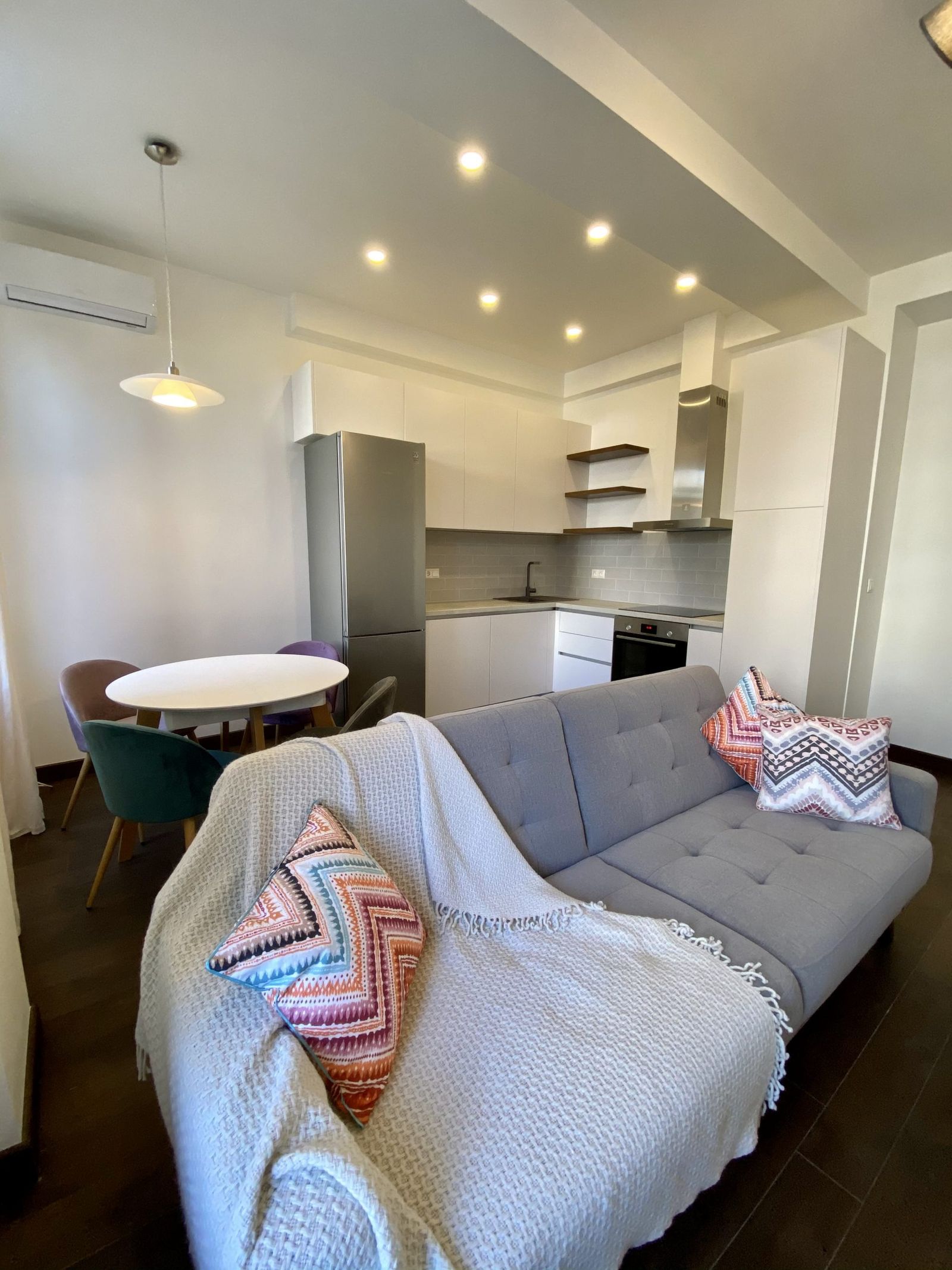 Living area with gray sofa, colorful pillows, and dining nook, Reitarska 30, Kyiv — Vestor.Estate
