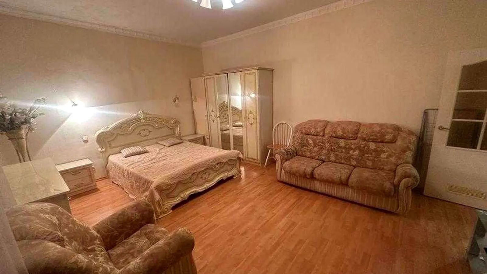 Bedroom with ornate headboard, plush sofa, and hardwood floors, Volodymyrska 37, Kyiv — Vestor.Estate