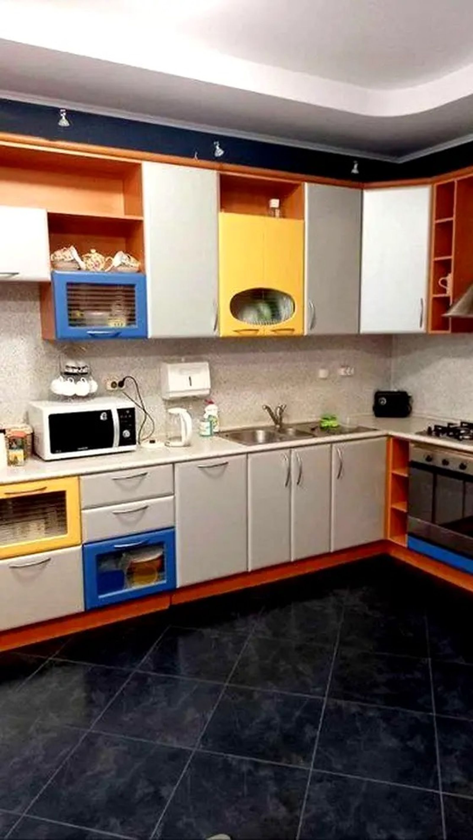 Modern kitchen with colorful cabinets and dark tiled floor, Yaroslaviv Val 21G, Kyiv — Vestor.Estate