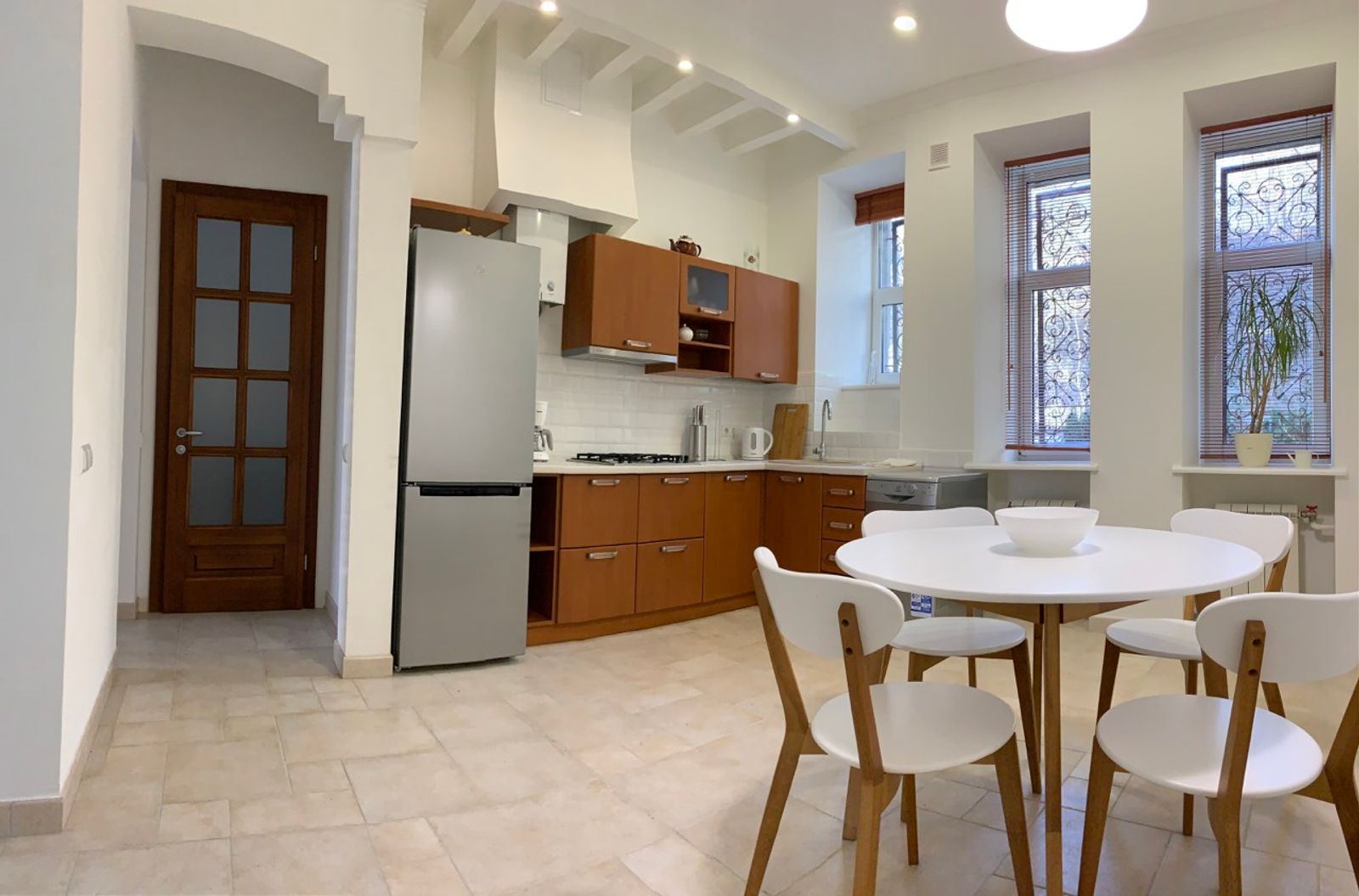 Modern kitchen with dining area, stainless steel refrigerator, and wood cabinets, Ivana Franka 9, Kyiv — Vestor.Estate