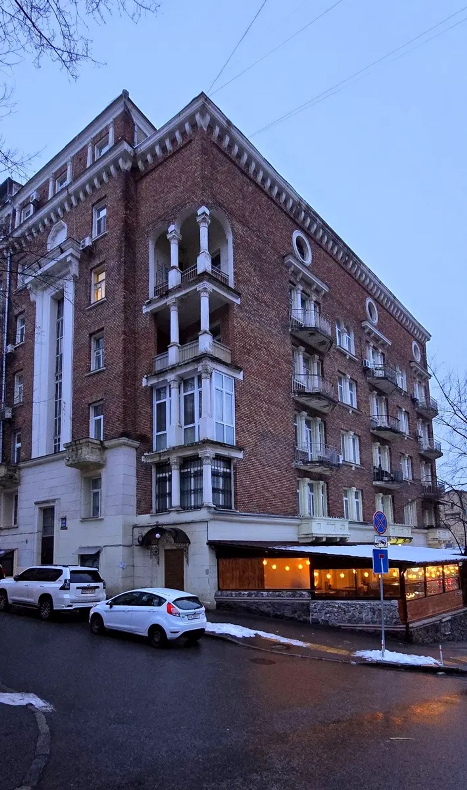 Brick building with ornate balconies and illuminated ground-floor cafe, Krutyi Uzviz 6/2, Kyiv — Vestor.Estate