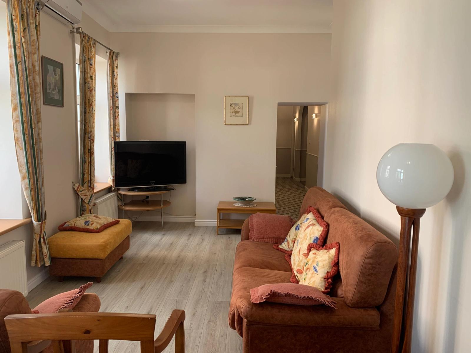 Living room with light wood floors and a large sectional sofa, Ivana Franka 40, Kyiv — Vestor.Estate