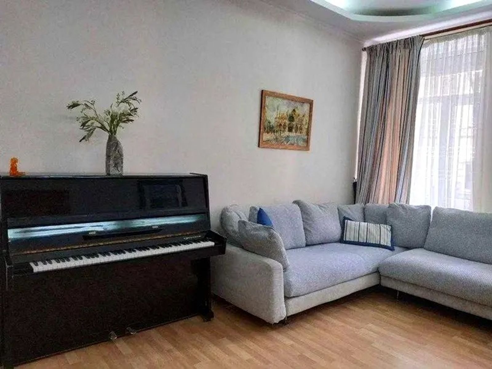 Living room with piano and sectional sofa, natural light, Malopidvalna 4, Kyiv — Vestor.Estate