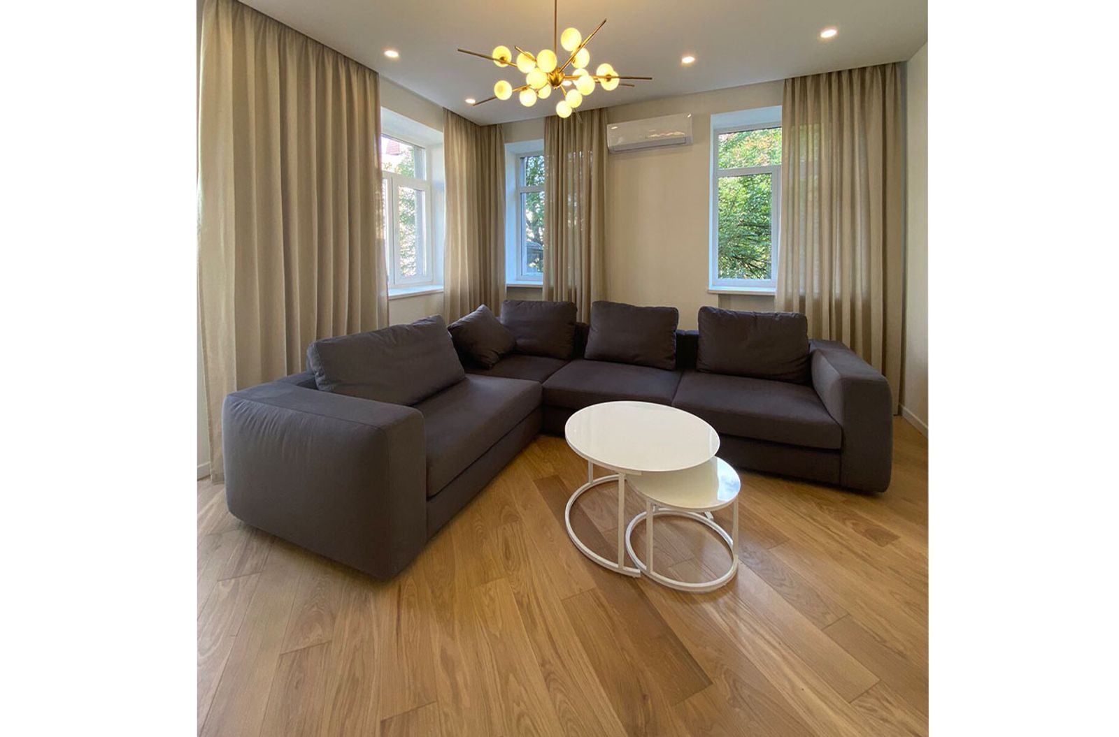 Living room with sectional sofa, nested tables, and wood floors, Kyiv — Vestor.Estate