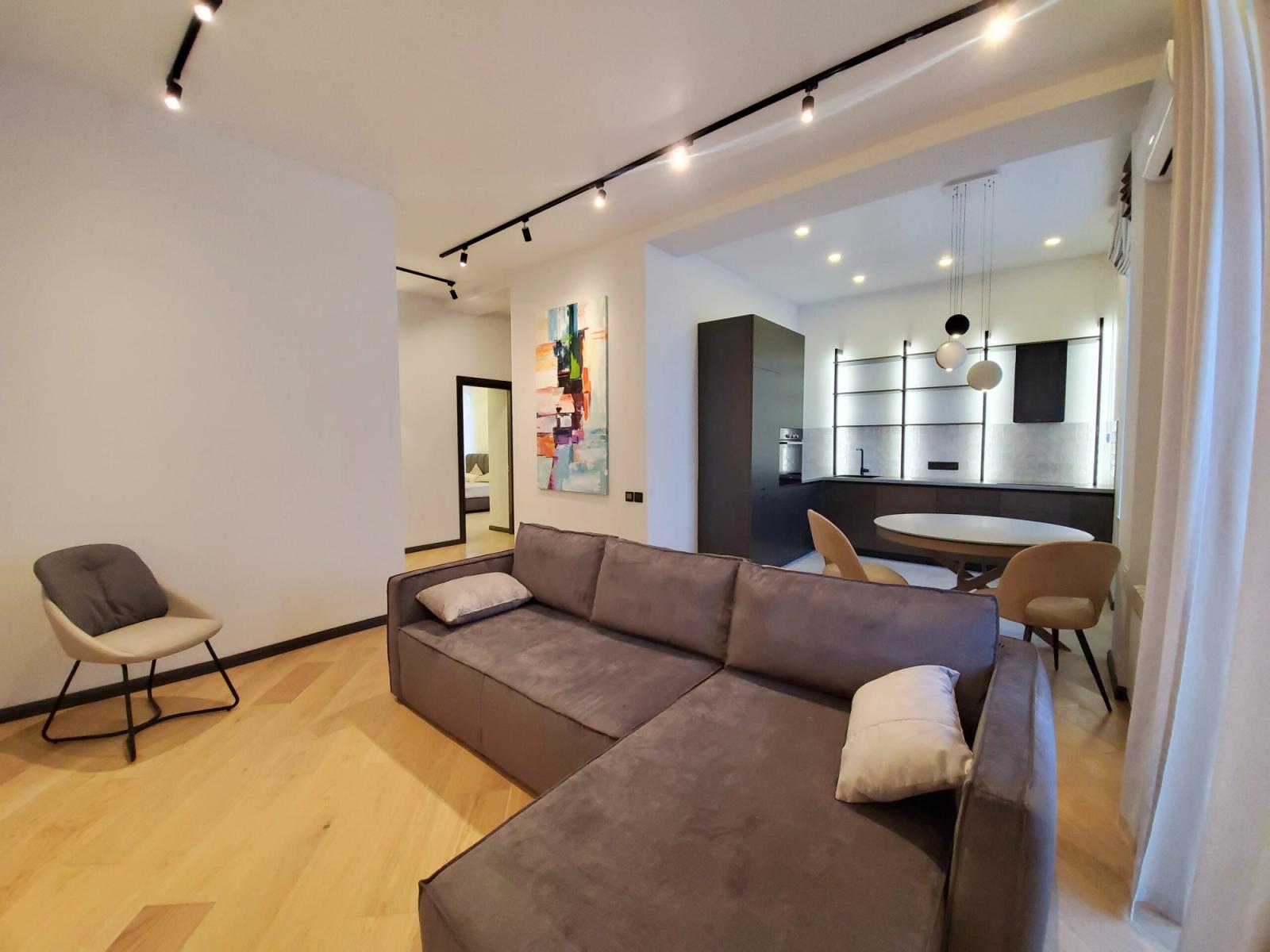 Living room and kitchen with modern track lighting and light wood floors, Volodymyrska 19A, Kyiv — Vestor.Estate
