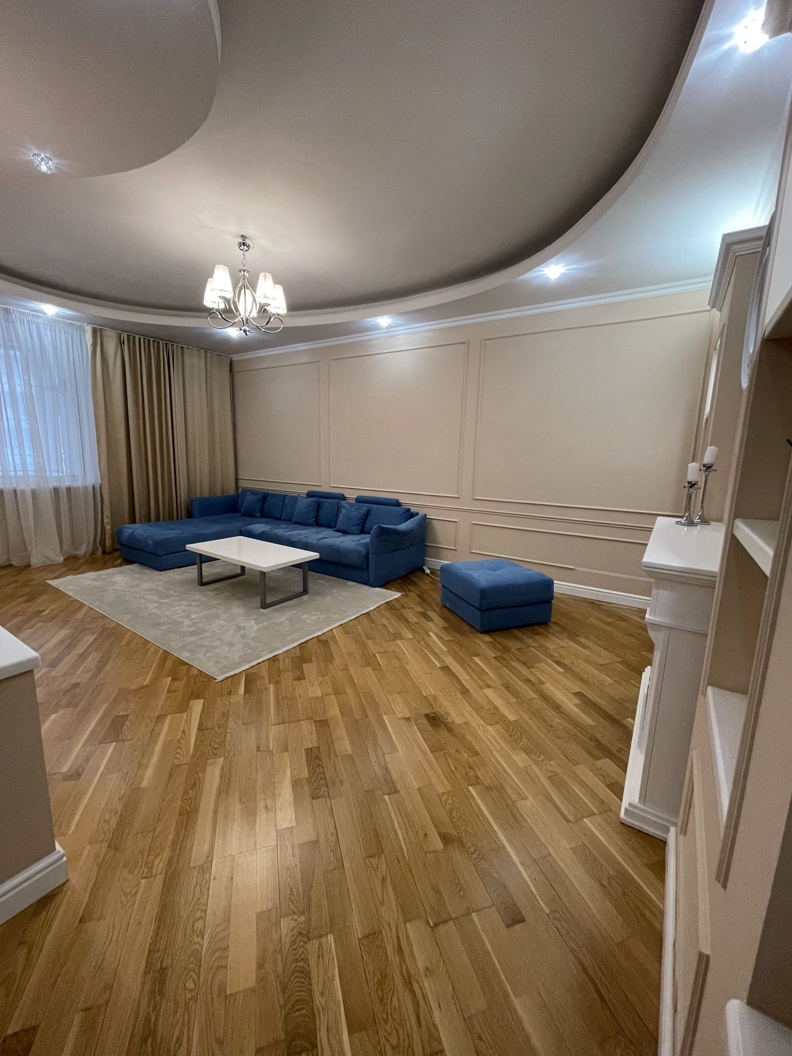 Living room with blue sectional and hardwood floors, Kyiv — Vestor.Estate