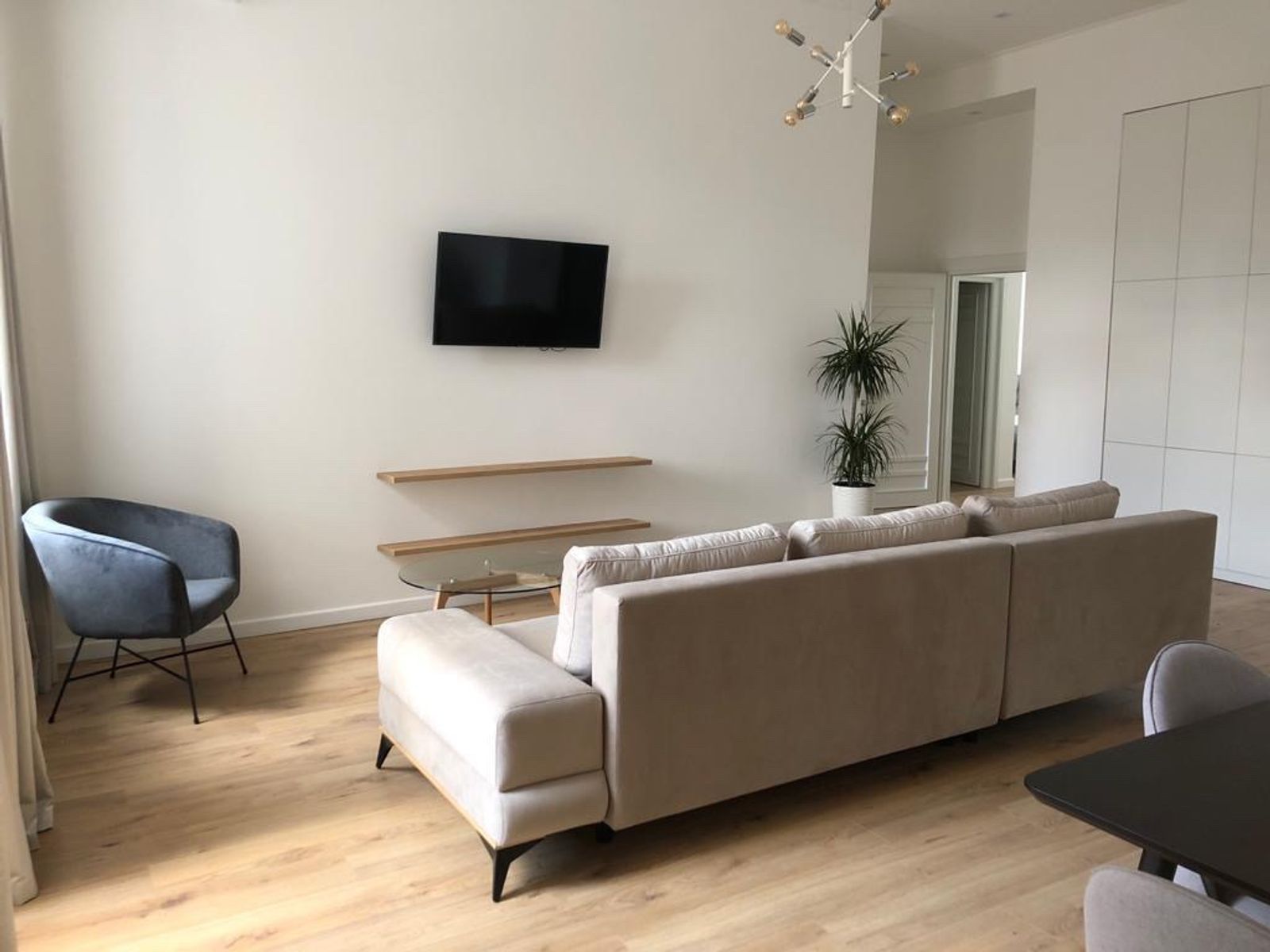 Living room with sectional sofa, armchair, and modern light fixture, Olesia Honchara 32A, Kyiv — Vestor.Estate