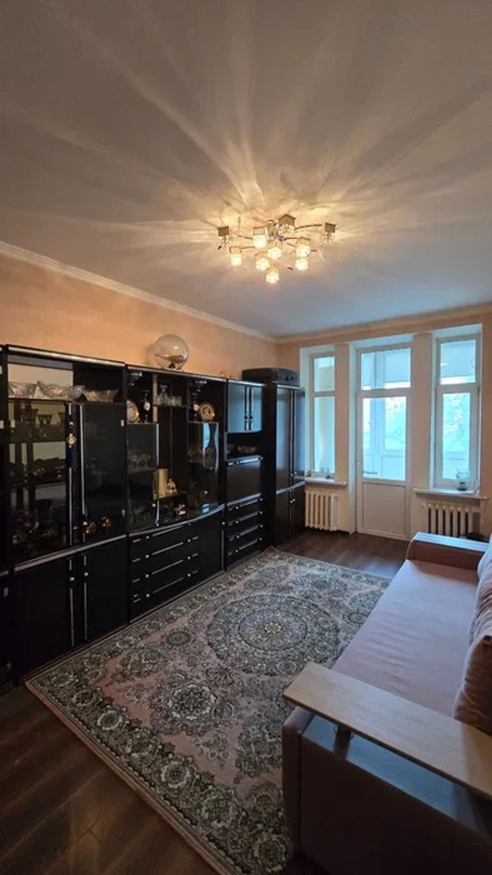 Living room with dark cabinetry, patterned rug, and bright chandelier, Velyka Vasylkivska 42, Kyiv — Vestor.Estate