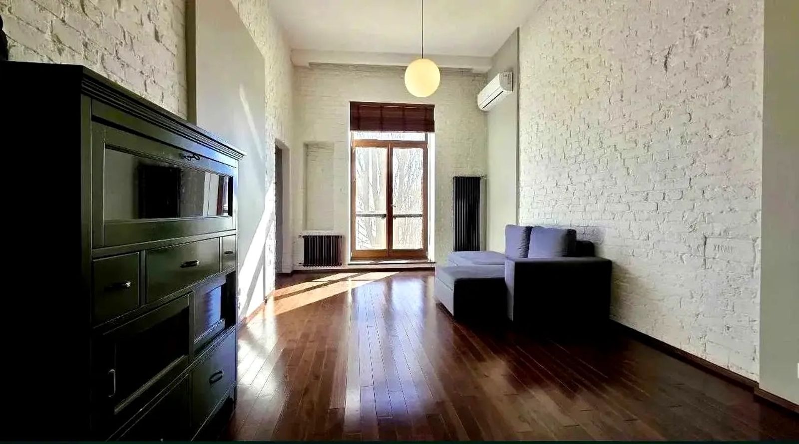 Living room with white brick walls and hardwood floors, Striletska 7/6, Kyiv — Vestor.Estate