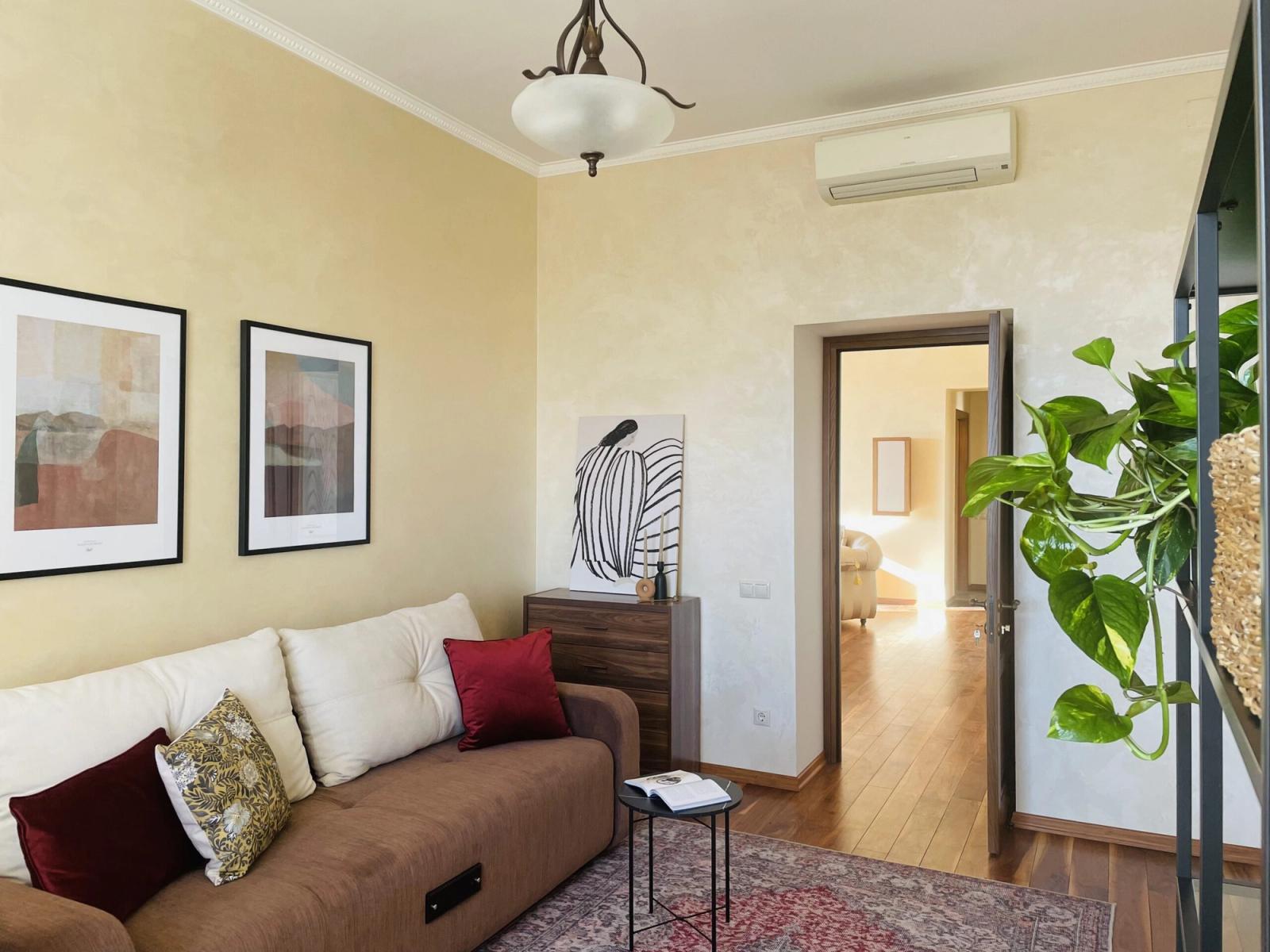 Living room with brown sofa, artwork, and natural light, Yaroslaviv Val 15a, Kyiv — Vestor.Estate