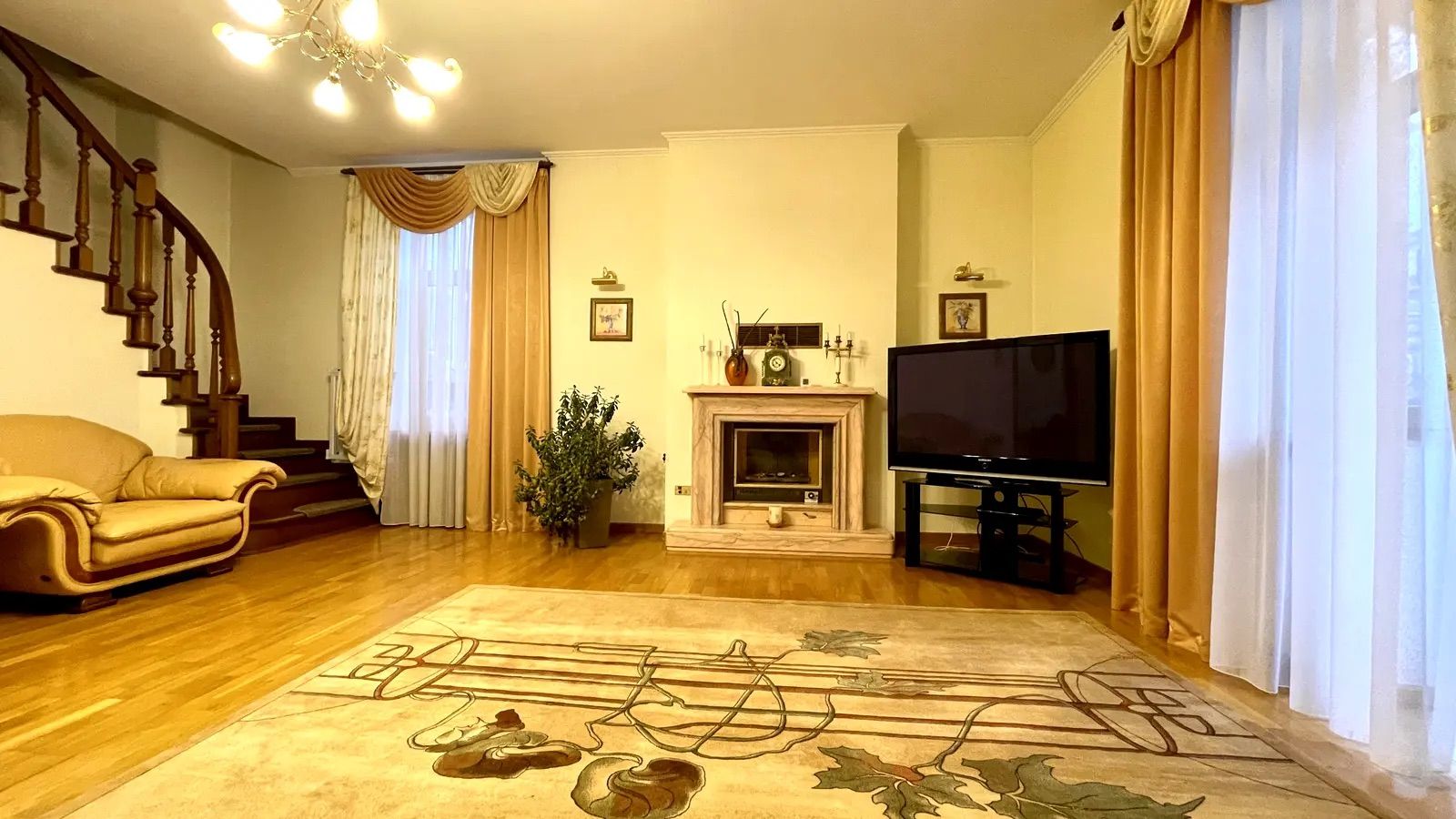 Living room with fireplace, curved staircase, and large rug, Liuteranska 4, Kyiv — Vestor.Estate
